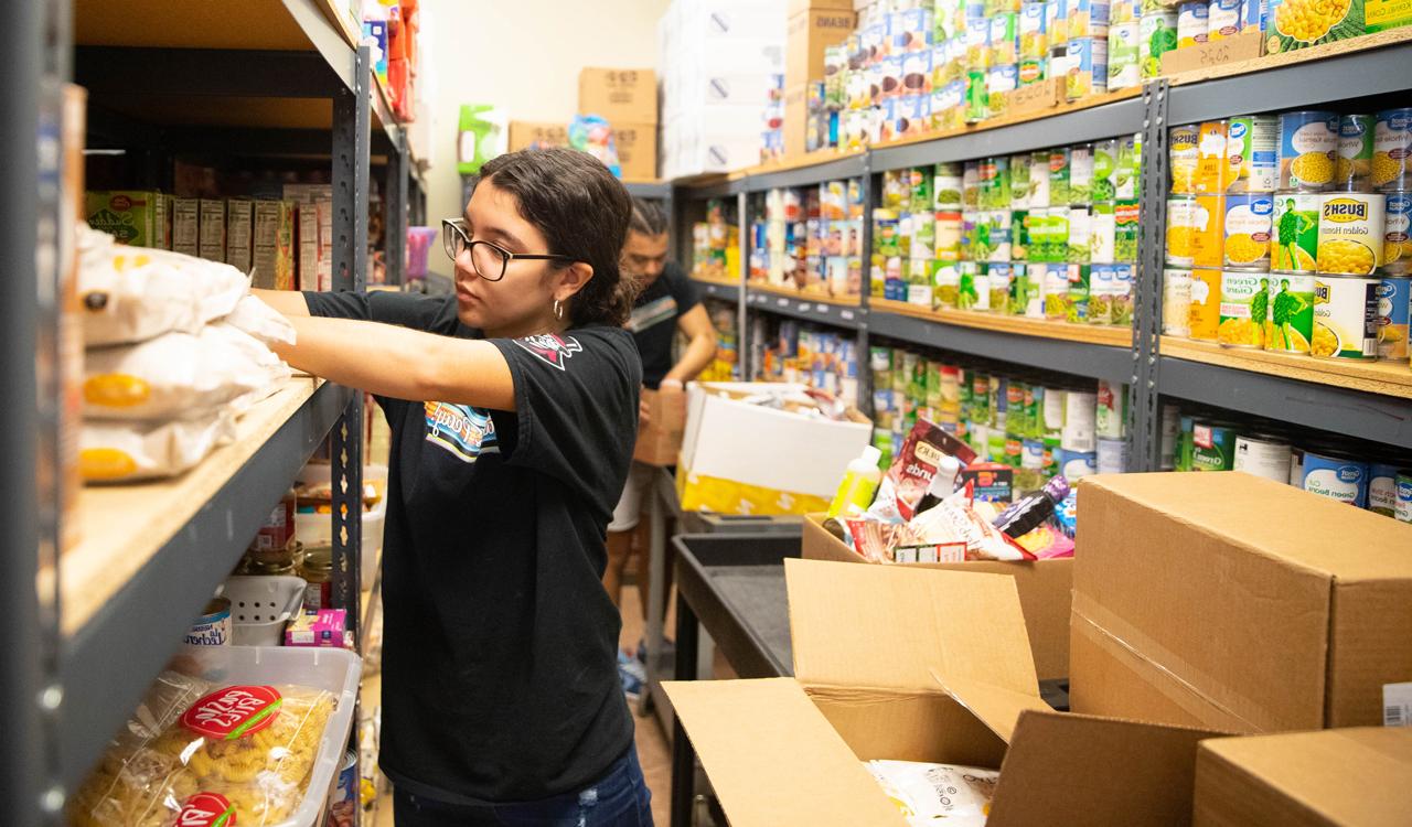 Student helping to restock shelves in the Food Pantry. 